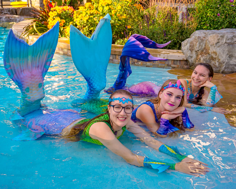 Three mermaids posing for a photo.